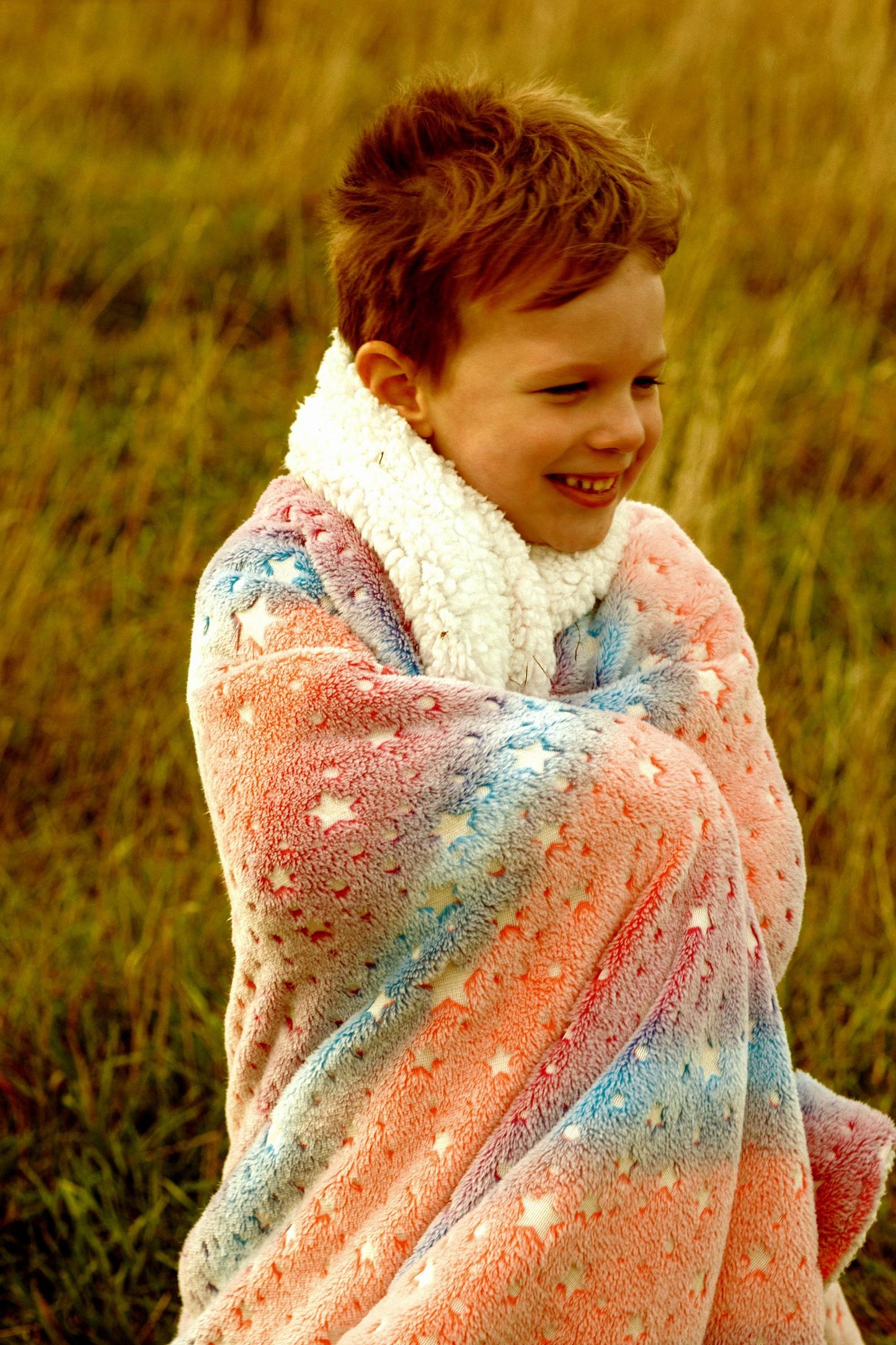 Glow in the dark blanket rainbow stars draped over young boy.