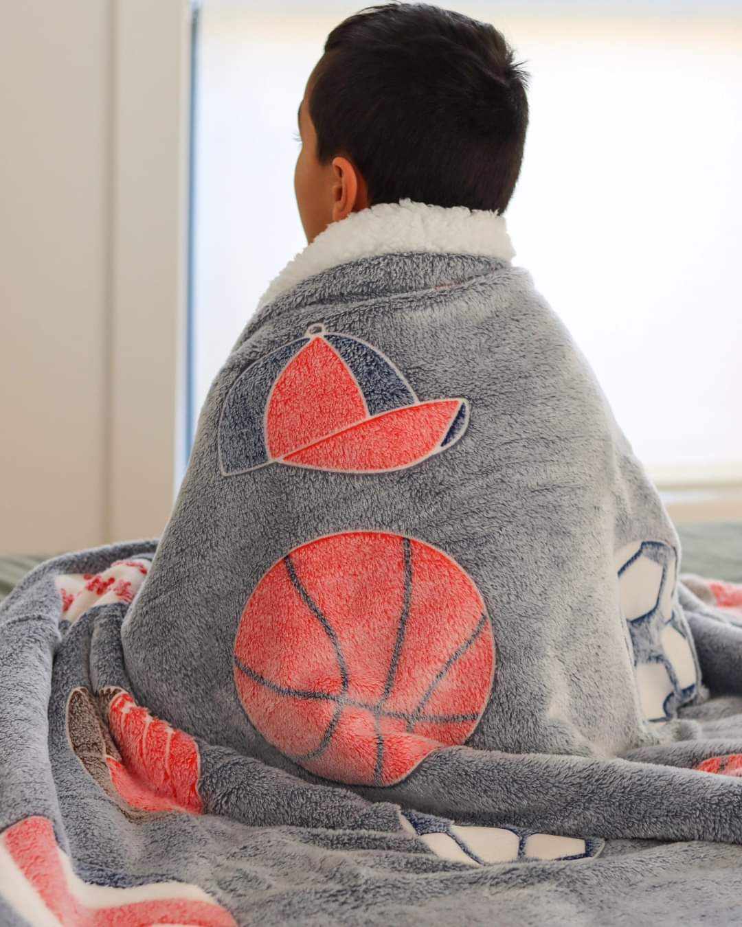 Glow in the dark blanket sports draped over young boy.